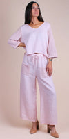 Woman wearing light pink linen pant set with crochet sleeves and pockets, sustainable fashion