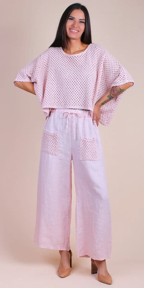 Woman wearing pink crochet knit top and wide-leg linen pants with front pockets