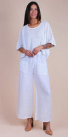 Woman wearing loose white perforated top and wide-leg linen pants with pockets