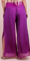 Back view of woman wearing wide-leg purple silk pants with side slits and high waist