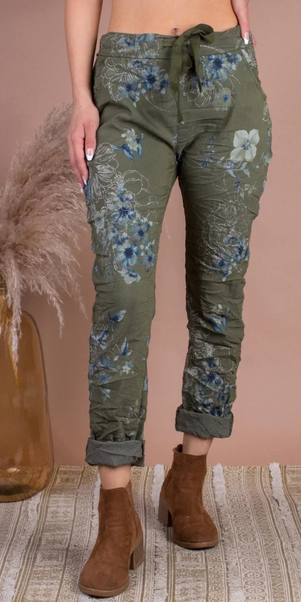Olive green floral jogger pants with drawstring waist and cuffed hems, styled with brown boots