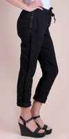 Woman wearing black drawstring pants with side stripe and cuffed hems, paired with black wedge sandals