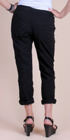 Woman wearing black cropped pants with rolled cuffs and black wedge sandals, rear view