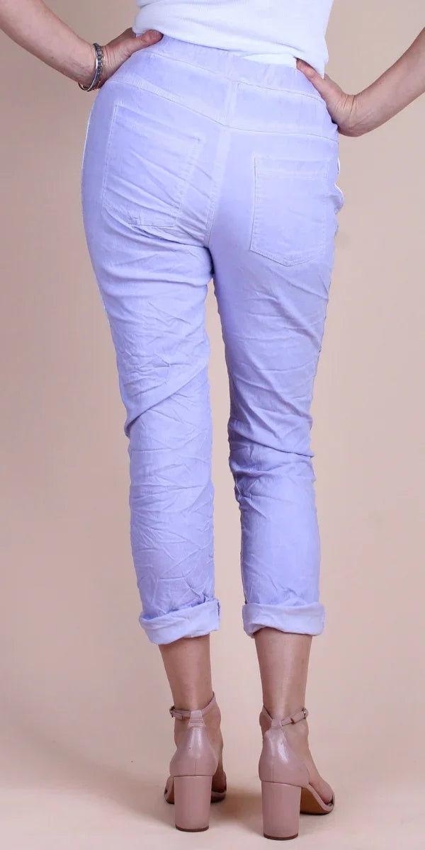 Back view of woman in light purple linen pants with rolled cuffs and nude block heels