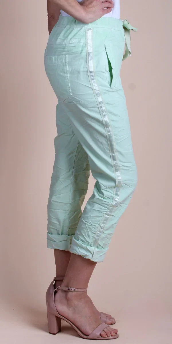 Light green cropped pants with side stripe, rolled cuffs, and side pockets on a model