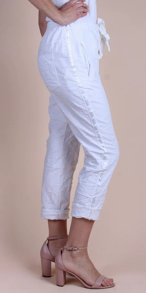 White cropped linen pants with side pockets and ankle cuffs, styled with blush block heels