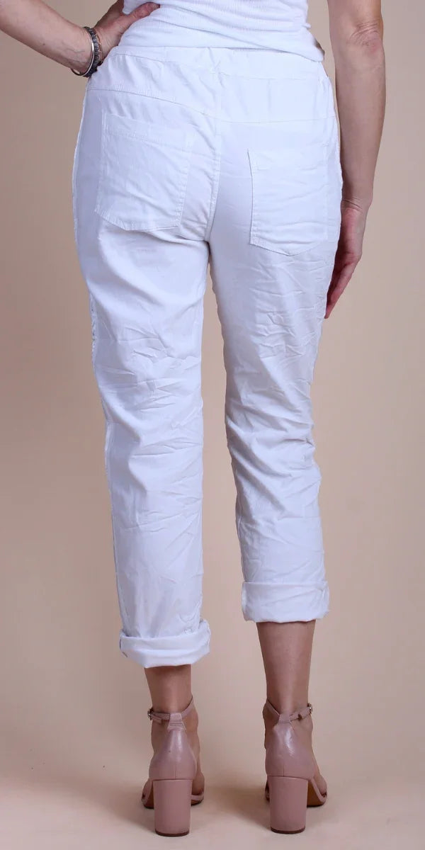 Back view of white cropped pants with rolled cuffs on woman, paired with nude block heels