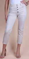 Woman wearing high-waisted beige pants with button fly and rolled cuffs, standing
