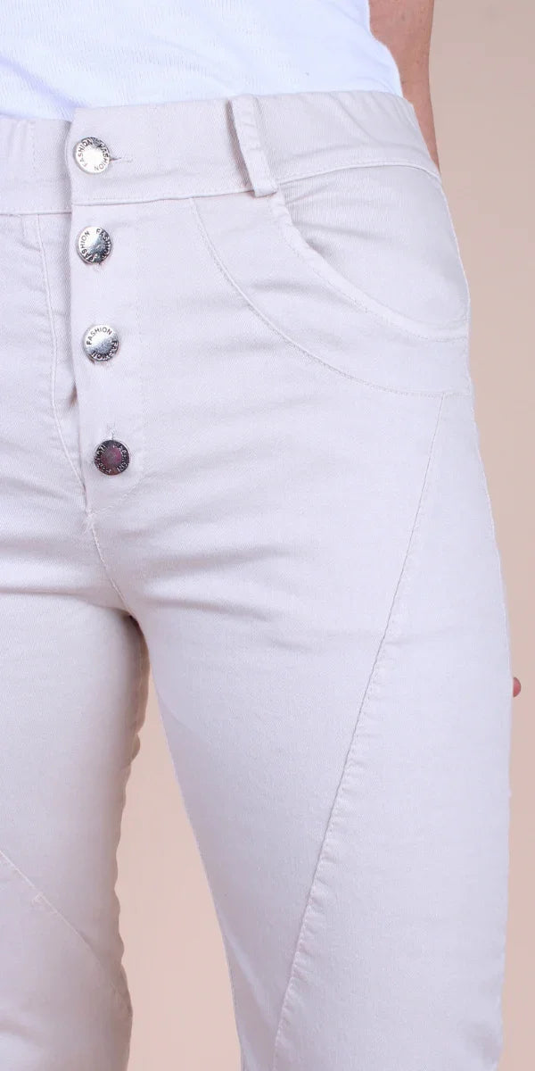 Close-up of beige women's pants with decorative buttons and front pockets