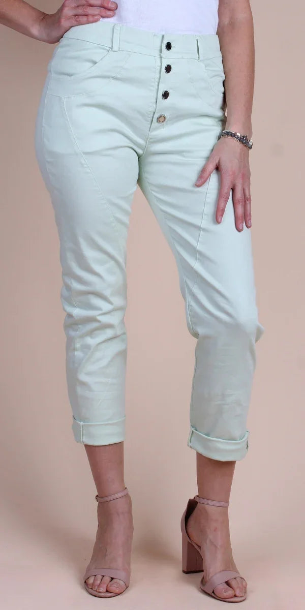 Woman wearing light mint high-rise button fly pants with cuffed hems and nude heels