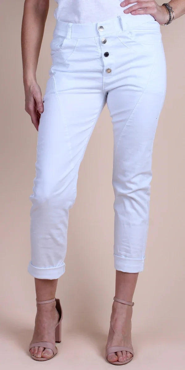 Woman wearing white high-waisted button front pants with rolled cuffs and nude heels
