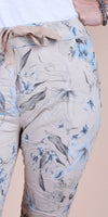 Beige floral print linen pants with blue and grey flowers and a tie waist, closeup view