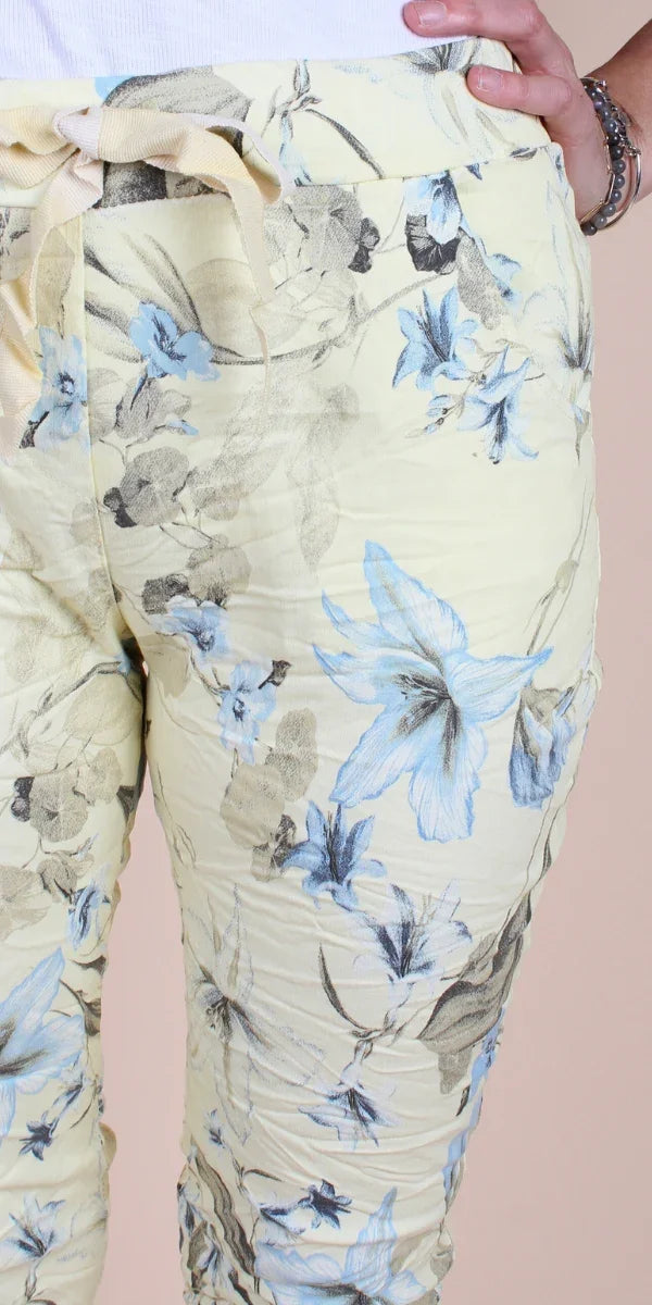 Yellow drawstring pants with blue and grey floral print, close-up view
