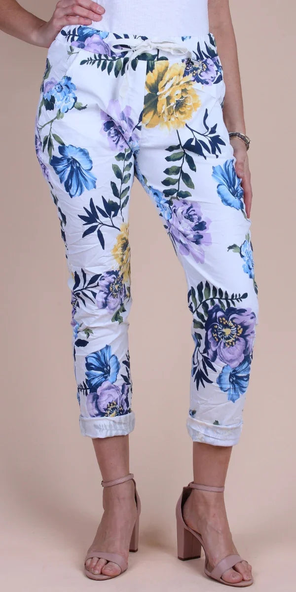 White floral print pants with blue, yellow, and purple flowers, rolled cuffs, and tie waist