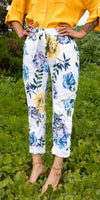 Woman wearing white floral print pants and a yellow linen shirt standing outdoors
