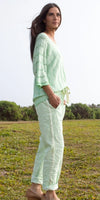 Woman wearing light green knit top and matching linen pants outdoors on grass