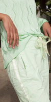 Woman wearing light green knit sweater and matching drawstring pants with side stripe