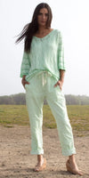 Woman outdoors in light green knit sweater and drawstring linen pants, spring fashion