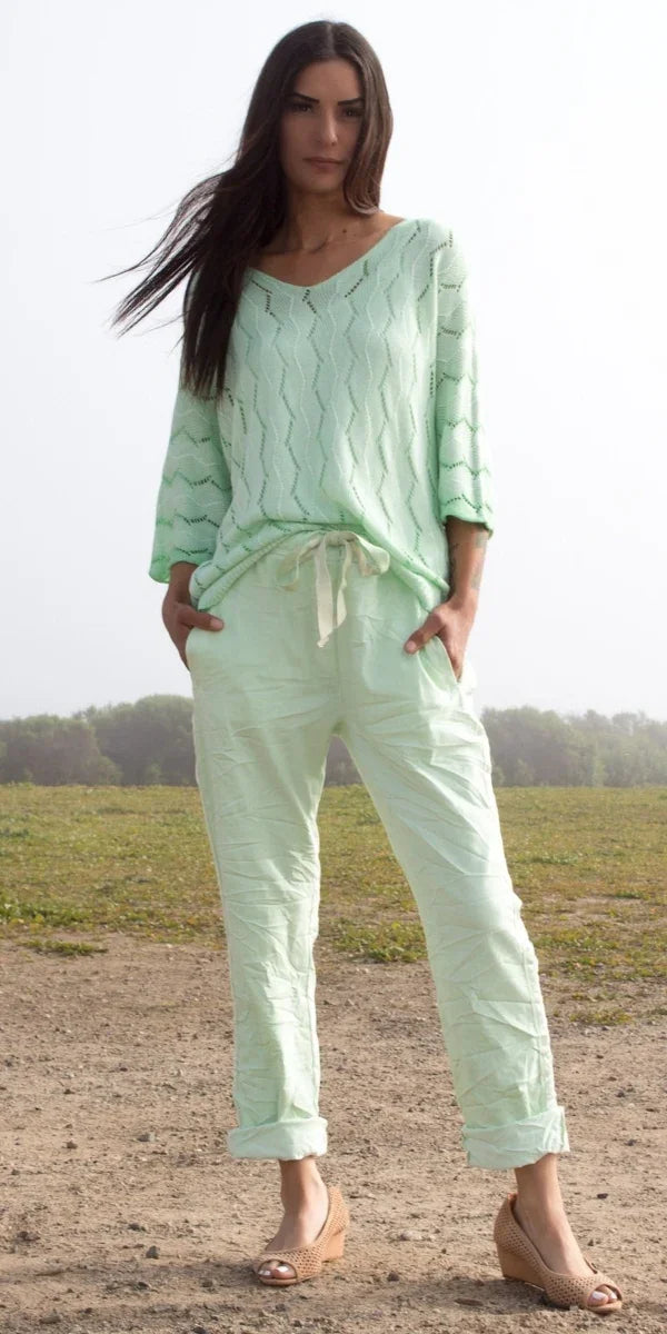 Woman outdoors in light green knit sweater and drawstring linen pants, spring fashion