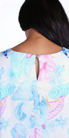 Close-up back view of a woman wearing a pastel floral blouse with a keyhole button detail