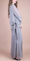 Woman wearing a light grey silk blouse with tie waist and matching wide-leg pants