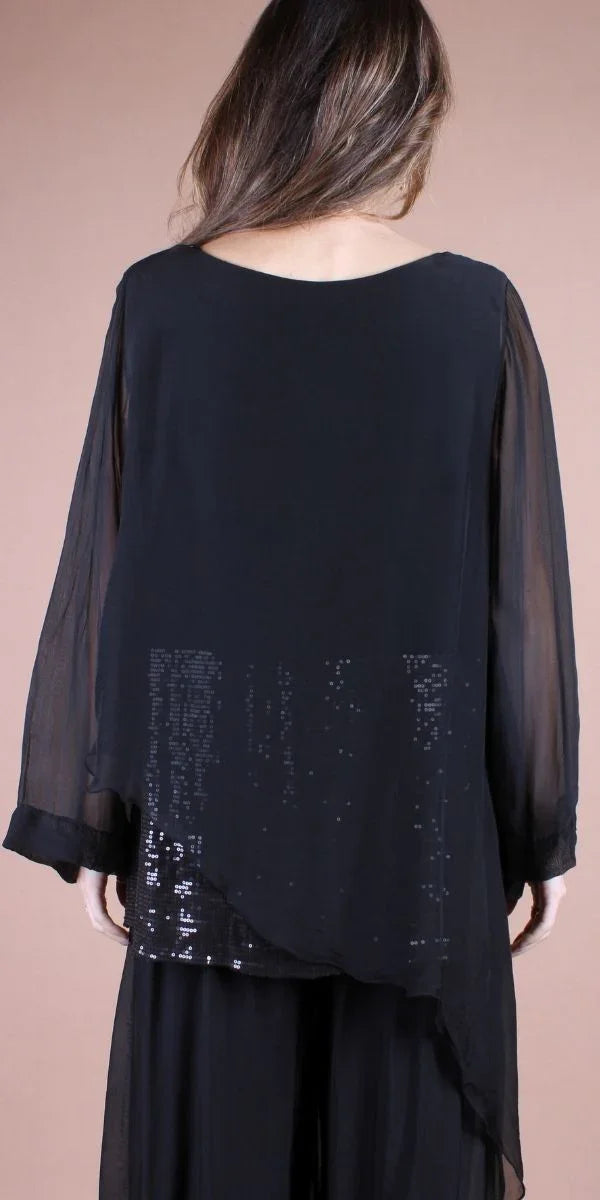 Back view of a woman wearing a black sheer tunic with sequin details and wide sleeves