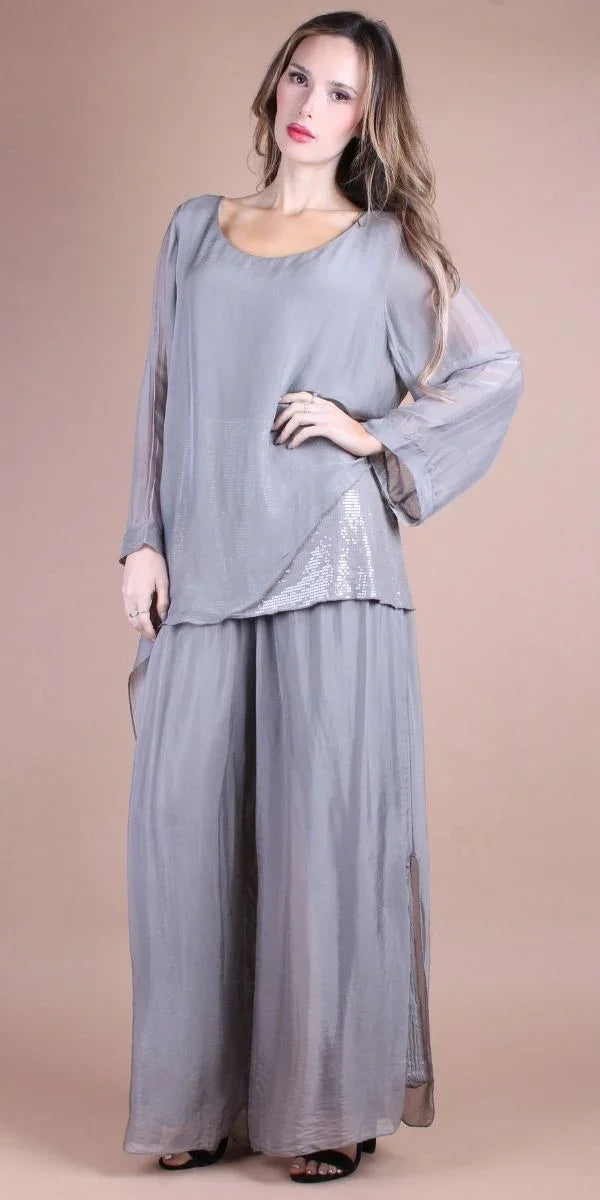 Woman wearing loose light gray silk top and wide-leg pants set, neutral background