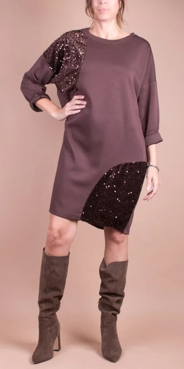 Woman wearing a mauve long sleeve dress with sequin patch accents and taupe knee-high boots