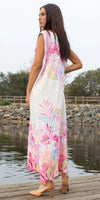 Woman in floral print maxi dress with pink and blue flowers, standing by a lake