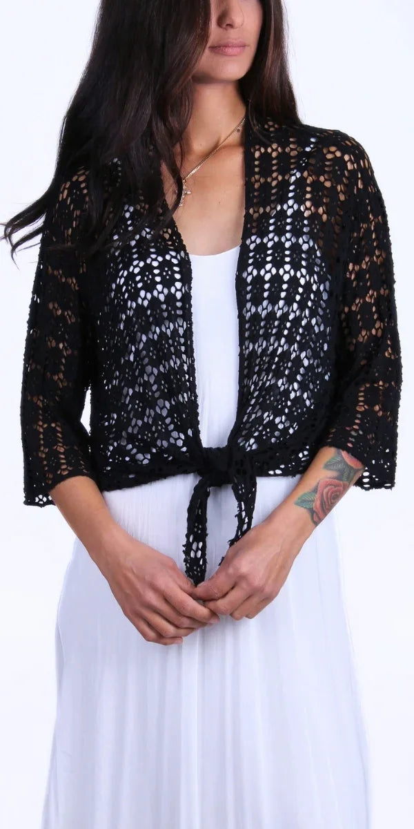 Woman wearing a black crochet knit tie-front cardigan over a white dress