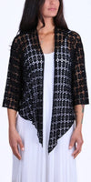 Woman wearing black open crochet cardigan over white dress, front view