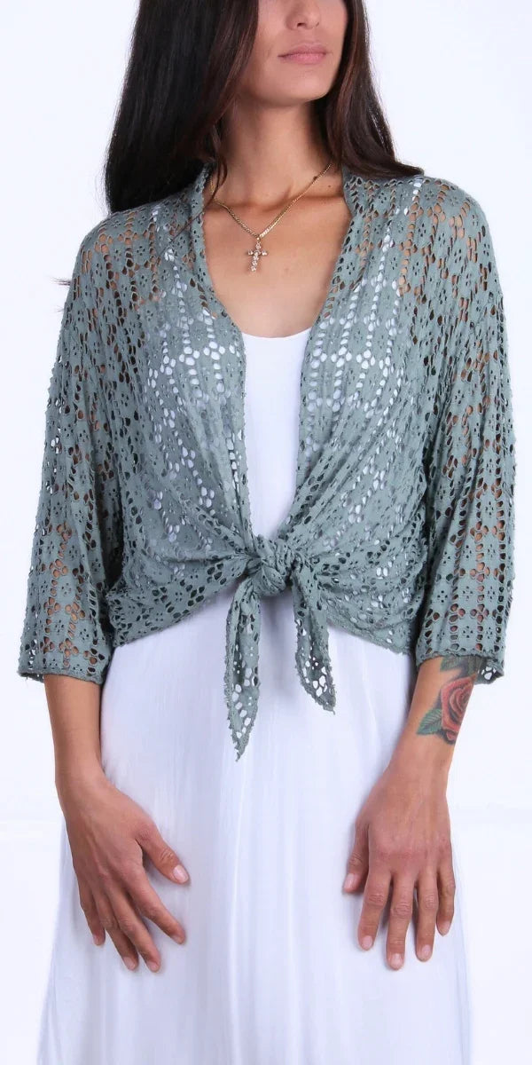 Woman wearing sage green lace knit tie-front cardigan over white dress