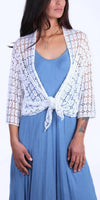 Woman wearing a white crochet lace cardigan over a light blue dress