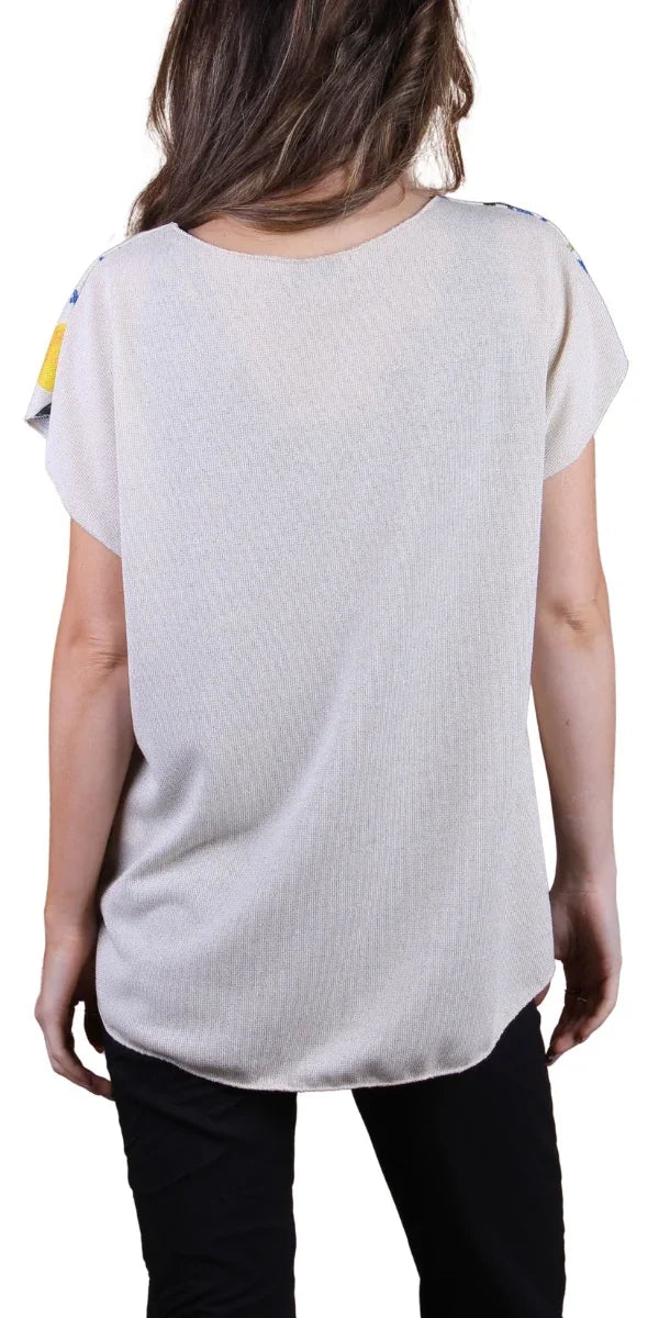 Back view of a woman wearing a loose-fitting beige short sleeve blouse with black pants