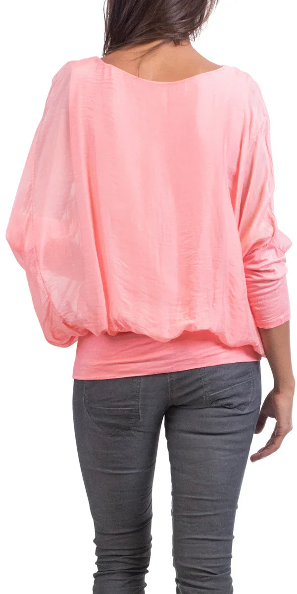Back view of woman wearing a loose pink silk top and gray jeans, casual fashion