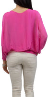 Woman wearing a vibrant pink sheer blouse with long sleeves and light beige pants, back view