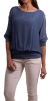 Woman in flowy blue long-sleeve blouse and white pants, front view, white background