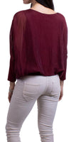 Woman wearing a burgundy sheer blouse with long sleeves and light skinny pants, rear view