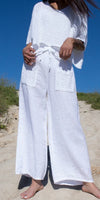 Woman wearing white wide-leg linen pants with crochet pockets and matching crochet top outdoors